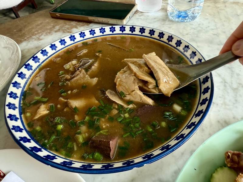 น้ำสตูหมูร้อน ๆ ในชามลายคราม ตักเนื้อและเครื่องในขึ้นมาเต็มช้อน